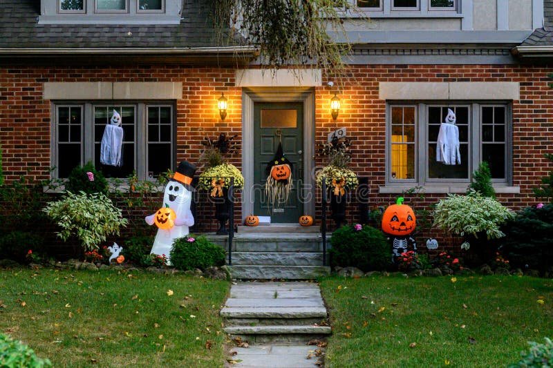 Halloween front entrance with ghost and pumpkin inflatables and window ghosts, installed by LitUp Vancouver